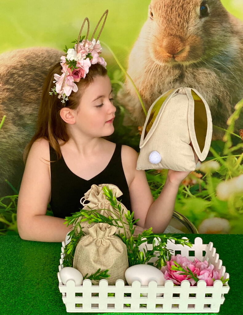 Child holding and admiring a bunny ear hessian bag filled with supplies for the Easter Fairy Garden activity.