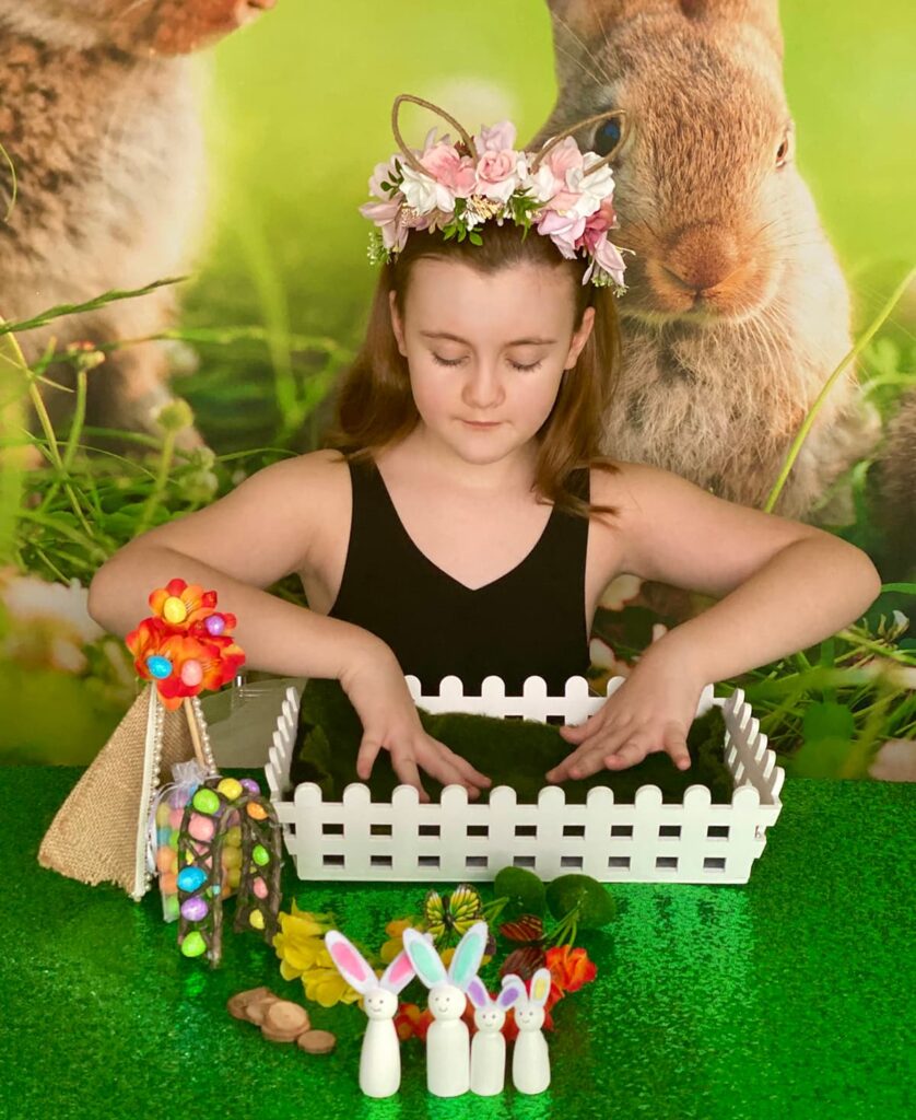 Child placing a single piece of green faux moss that covers the base of the Easter fairy garden crate.