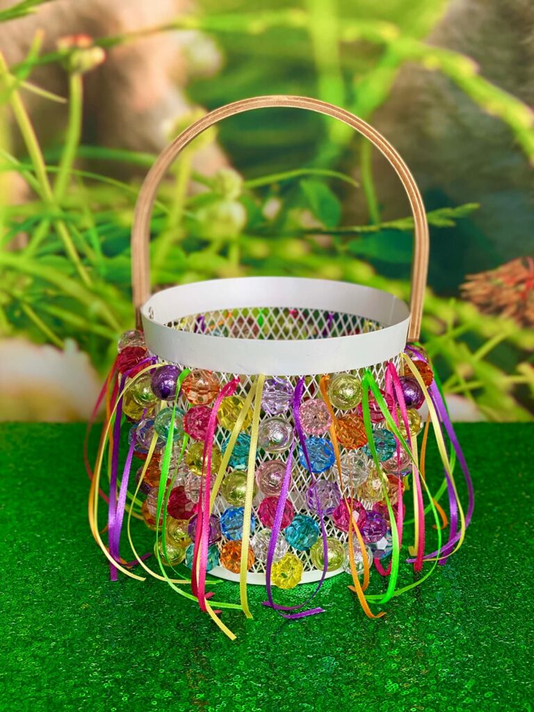 Completed Easter basket displayed on a green sequin tablecloth, with part of the spring-themed bunny backdrop visible in the background.