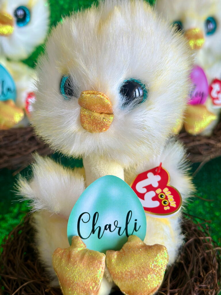 Plush yellow chick Easter party favour sitting in a brown faux nest with a green egg-shaped name tag that says “Charli”.