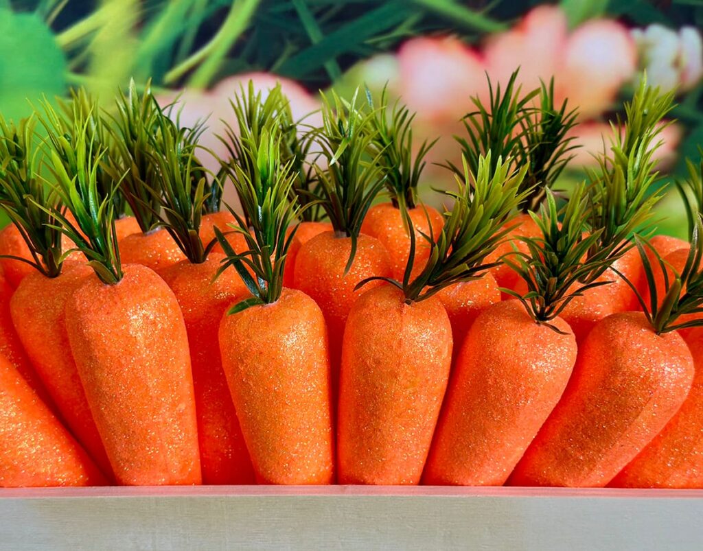 Close-up of orange foam carrots with green tops nestled together inside a wooden crate.