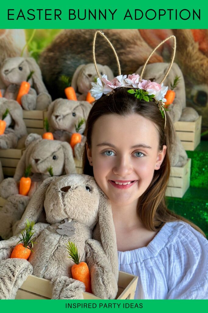 Young girl smiling in front of an Easter Bunny Adoption Party table, holding a crate with a plush bunny and faux carrots.