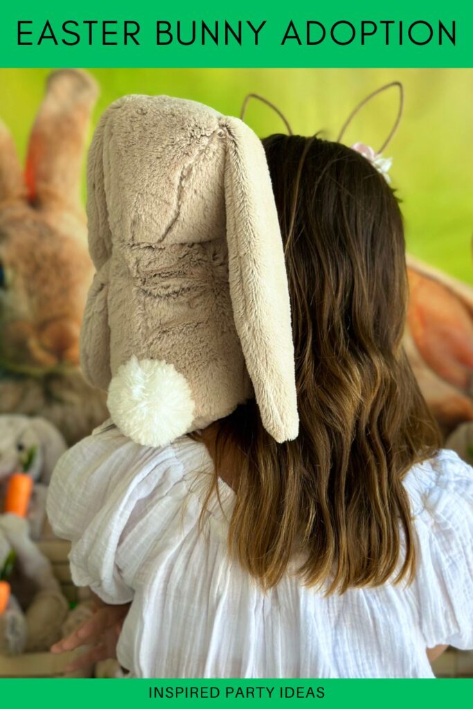 Girl at an Easter bunny adoption party holding a bunny on her shoulder, both looking toward the adoption table, with the bunny’s fluffy cottontail visible.