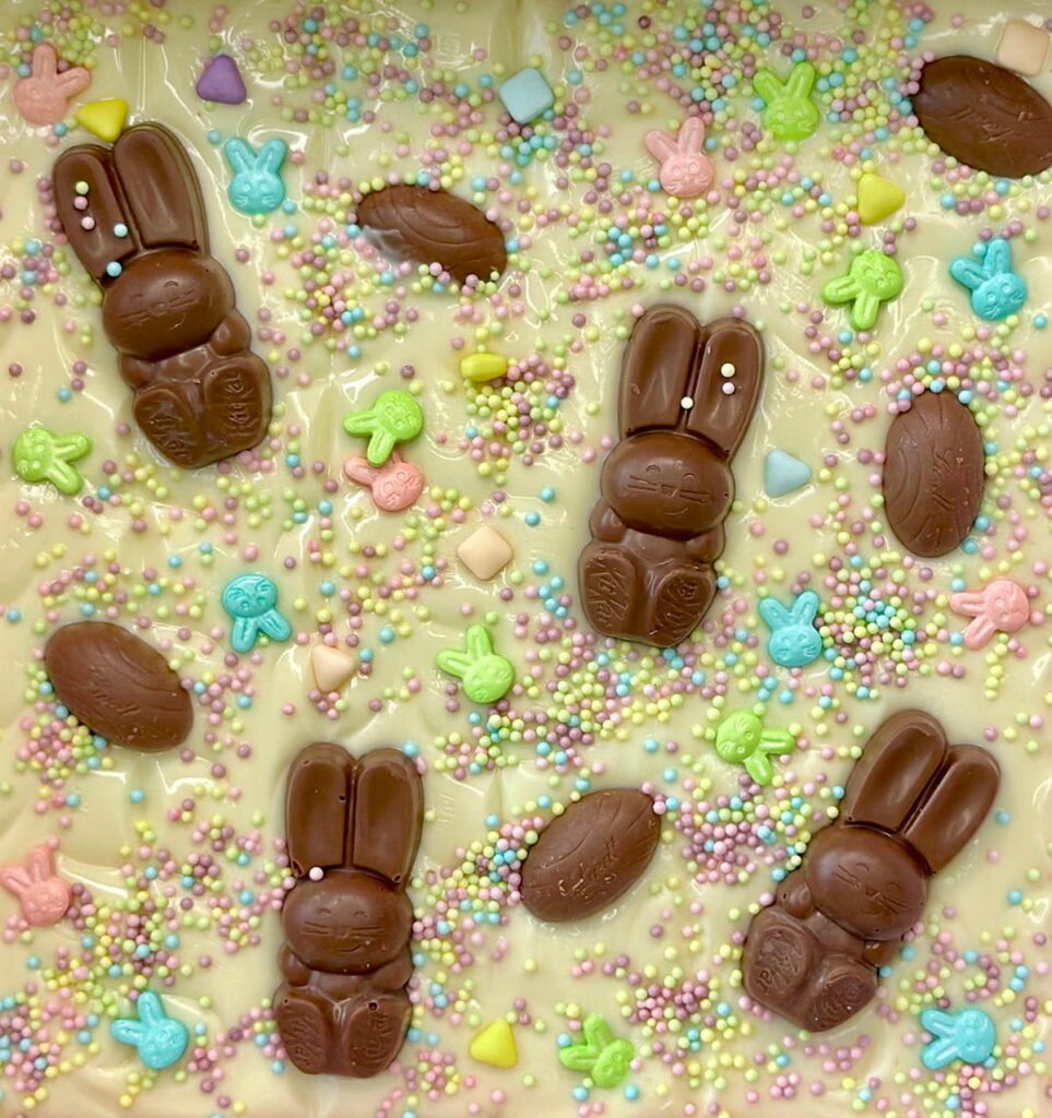 White chocolate Easter bark slab decorated with Kit Kat Easter bunny pieces, pastel sprinkles, and colorful Easter eggs, perfect for a festive kids’ treat.