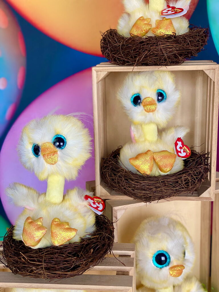 Close-up of Easter Chick Adoption party display featuring plush chicks in faux nests and wooden crates, with colorful decorations and a playful spring theme.