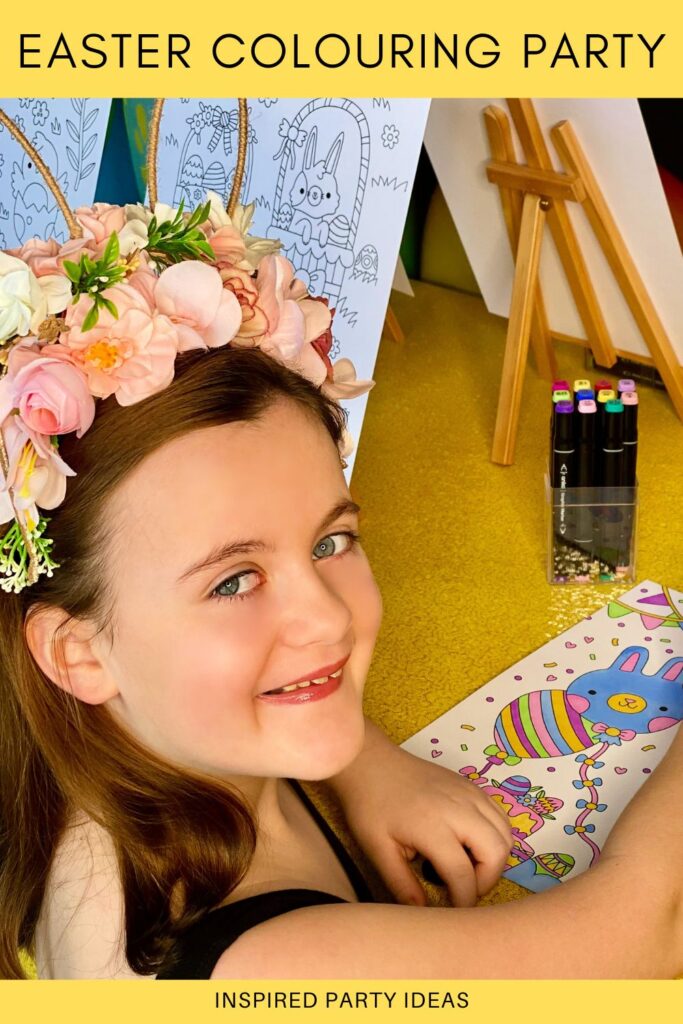 Young girl smiling while colouring at an Easter colouring party table with markers, surrounded by uncoloured Easter-themed art on easels and a yellow sequin tablecloth.