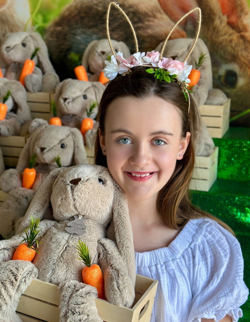lose-up of a girl holding a crate with a plush bunny and faux carrots in front of the Easter Bunny Adoption table.