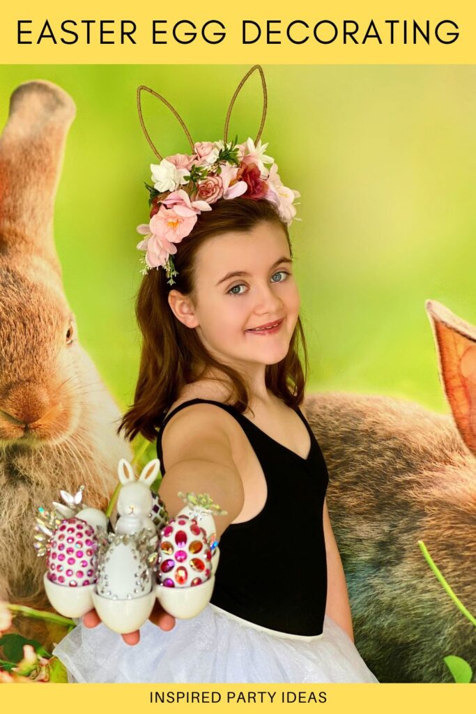 Pinterest image of a smiling girl standing side-on in front of a spring bunny backdrop, holding out a bunny egg holder filled with her decorated Easter eggs.