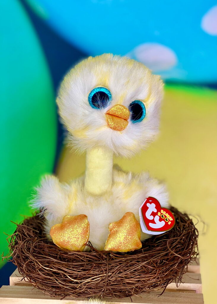 Yellow Beanie Boo chick sitting in a faux bird's nest with a colorful Easter egg backdrop behind it, perfect for a festive Easter party setup.