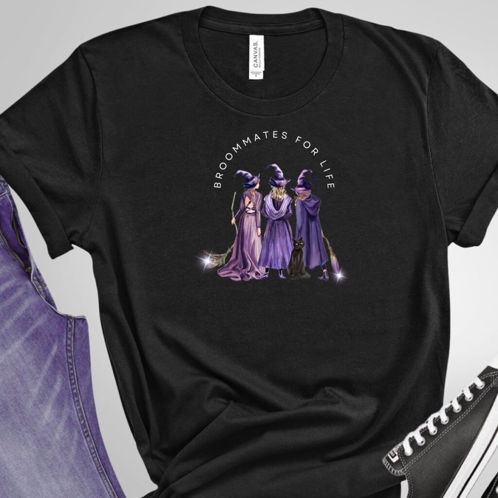 Black kids’ t-shirt with a witch-themed design showing three witches and the phrase 'Broommates for Life,' available from Inspired Party Merch.