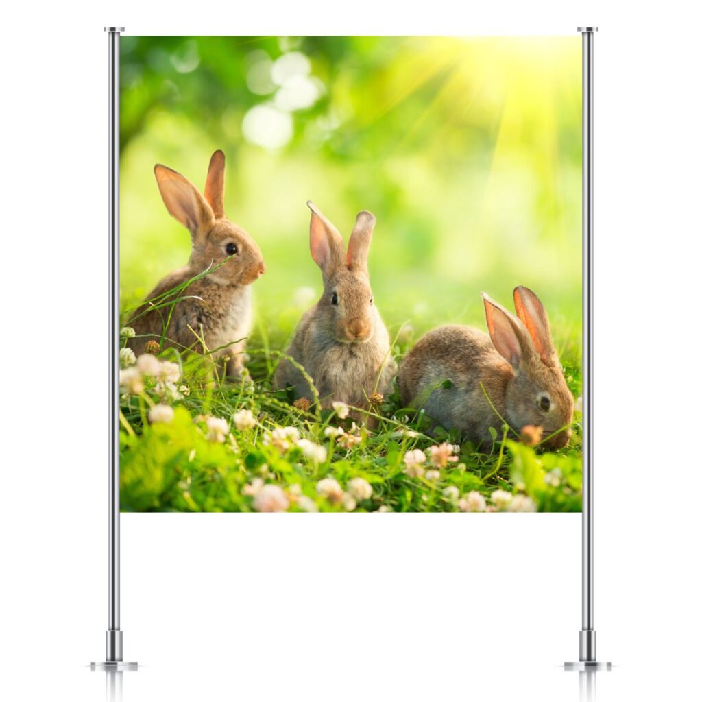 Easter backdrop featuring three bunnies in a spring meadow, displayed on a silver backdrop stand, showcasing Inspired Party Backdrops.