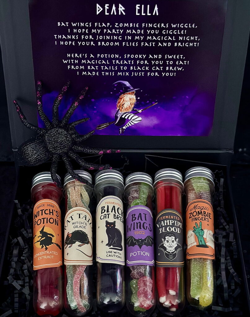 Black gift box filled with clear potion vials with themed labels, then filled with Halloween candy like red frogs, gummy cats, and sour spaghetti, used as sweet spell party favours for a witch-themed kids’ party.