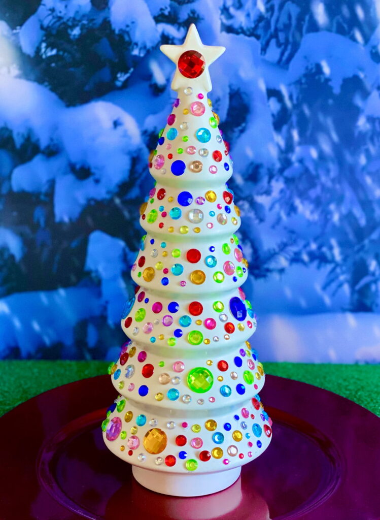 Decorated Crafty Christmas Tree from a kids’ party with bright colourful gems on a red charger plate.