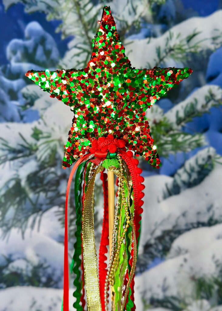 Sparkly Christmas wand in red, green, and gold with ribbon accents, used as a children’s party favour.