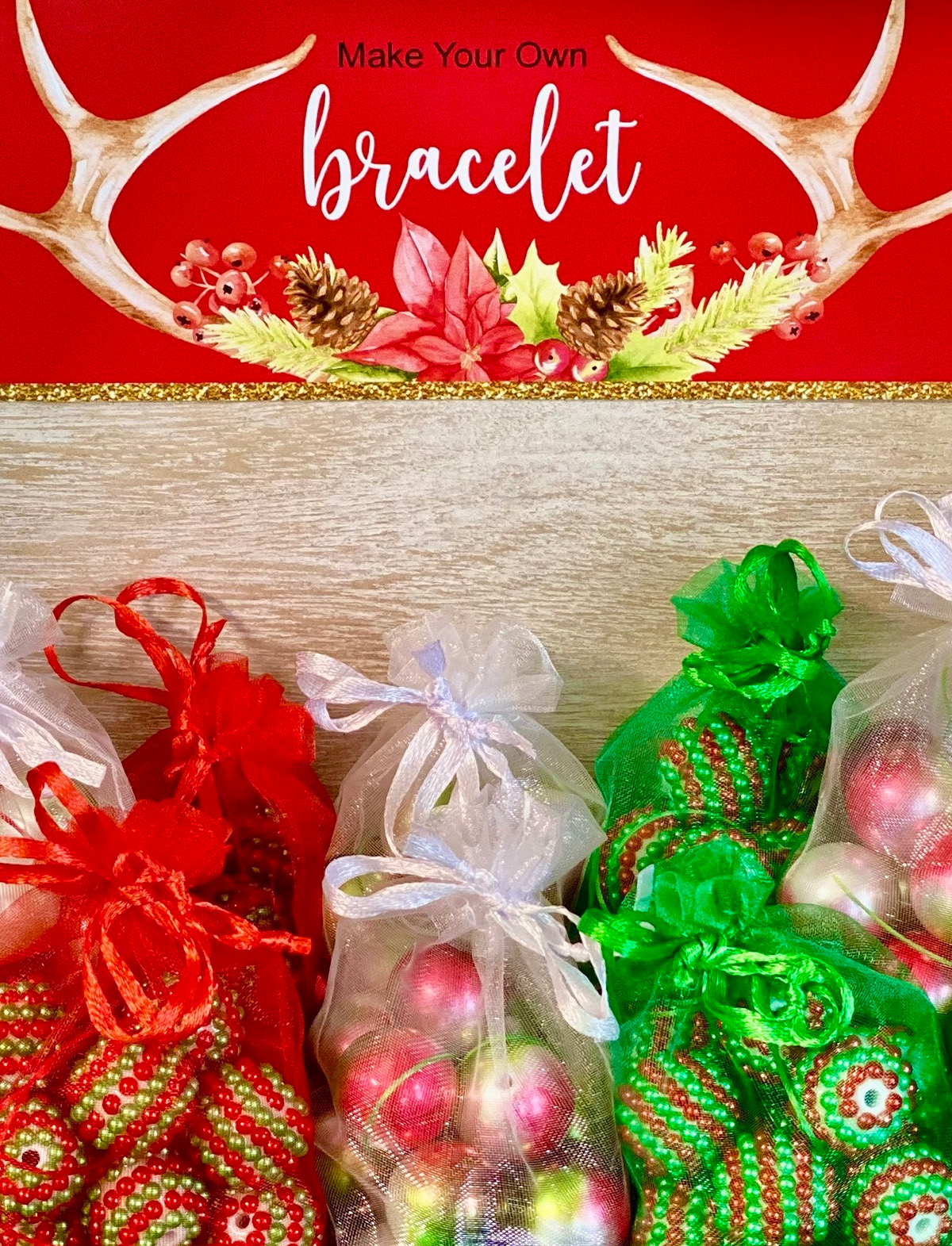 Christmas jewelry bracelet kits in organza bags on display with a sign for the kids’ holiday jewelry-making activity.