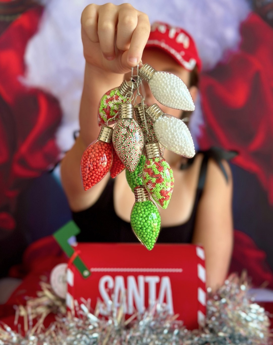 Clear Christmas ornaments filled with sand art decorating supplies, including foam balls and clay mix-ins for a kids Christmas craft activity.
