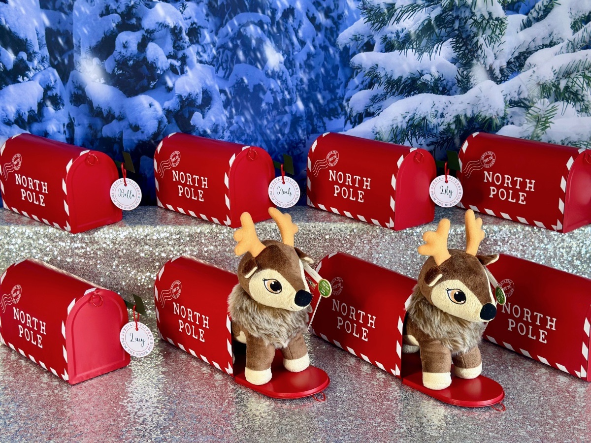 Red Santa mailboxes holding plush reindeer, designed as take-home Christmas party favours for children.