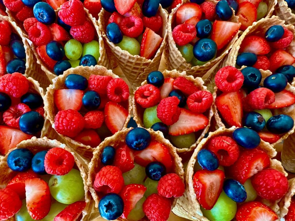 Overhead view of waffle cones filled with fresh berries for a fairy unicorn themed treat table.