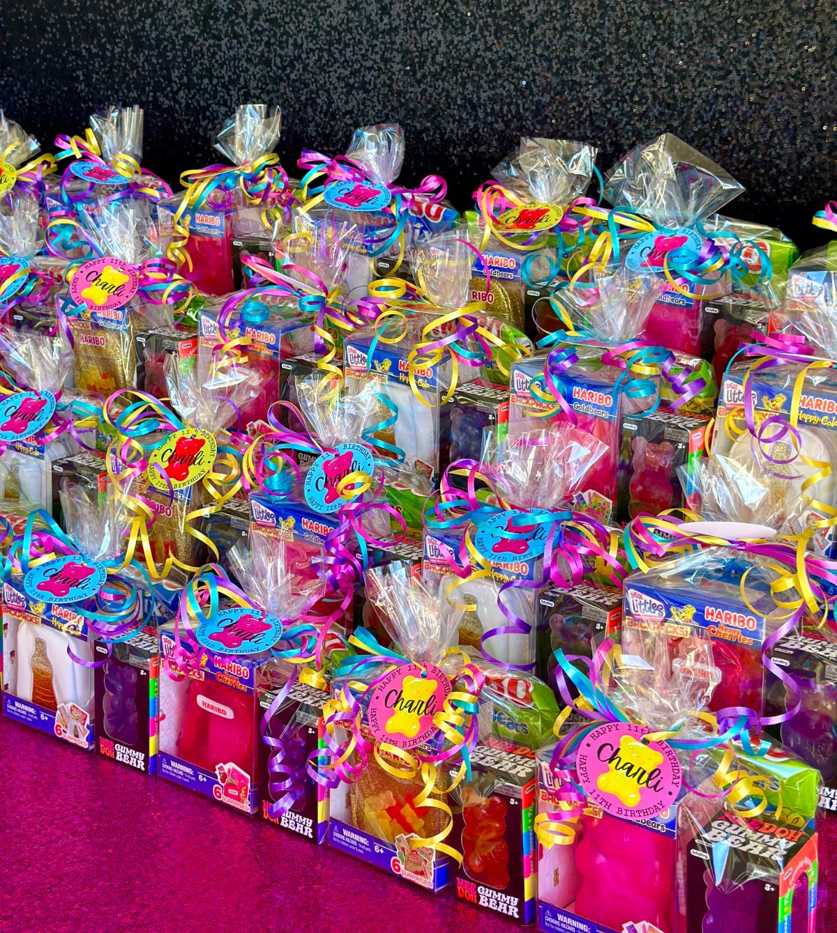 Angled view of kids Haribo party favours with gummies, mini backpacks, and Needo gummy bears in cellophane bags.