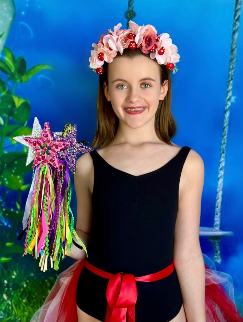 Smiling girl holding colorful DIY fairy wands at a kids party activity.