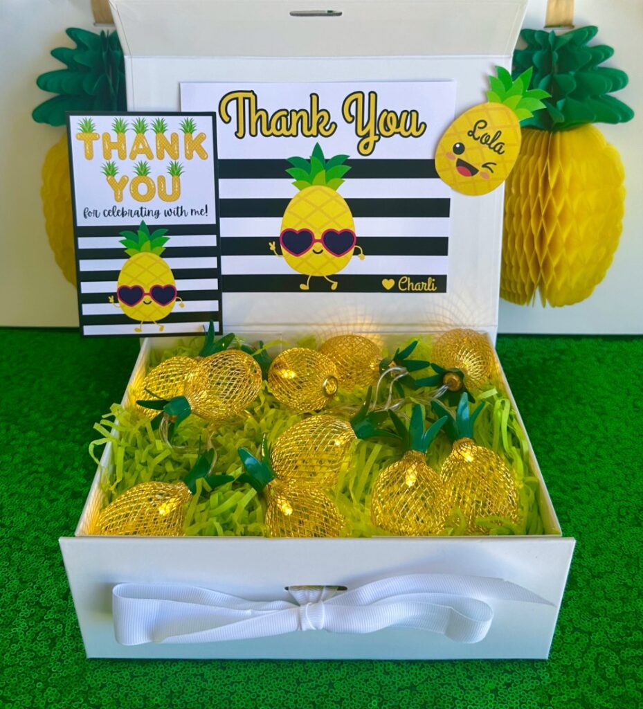 Kids pineapple party favour featuring pineapple string lights in a white gift box with a personalised thank you card and name tag.