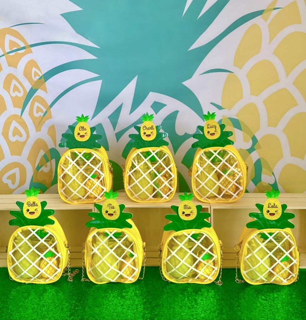 Pineapple party favours for kids featuring pineapple handbags filled with stationery supplies.