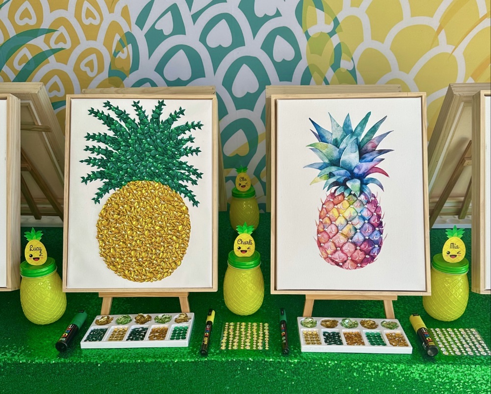 Two completed pineapple paintings displayed on wooden easels at a kids pineapple painting party.