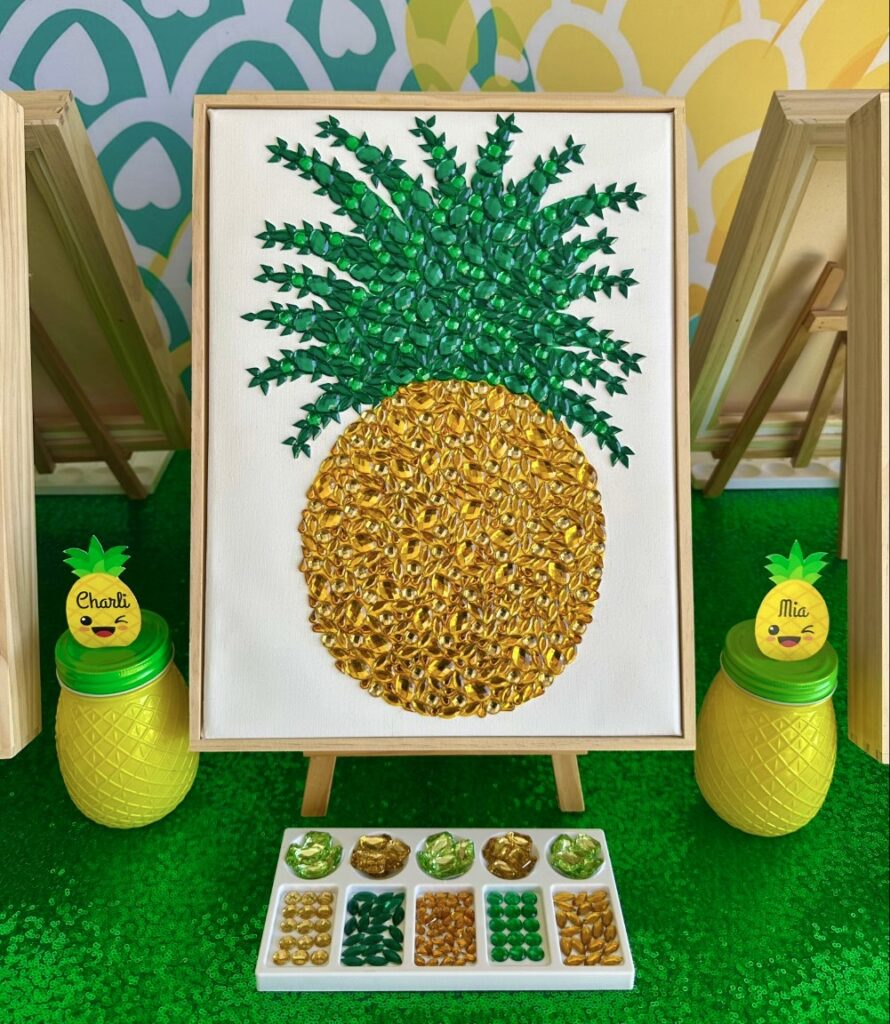 Colourful pineapple painting with gem embellishments displayed on a wooden easel at a kids pineapple painting party.