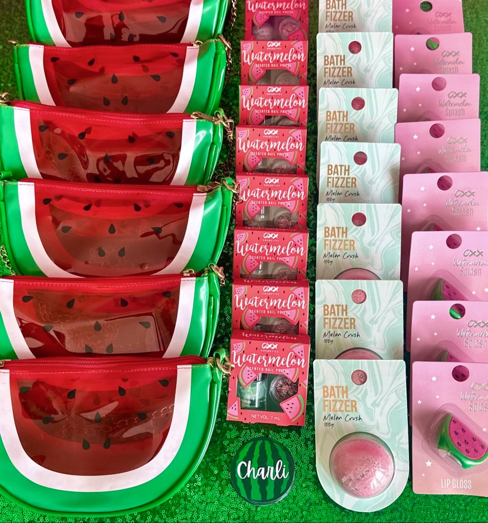 Watermelon spa bag supplies arranged on a green sequin tablecloth with handbags, nail polish, bath bombs and lip gloss.
