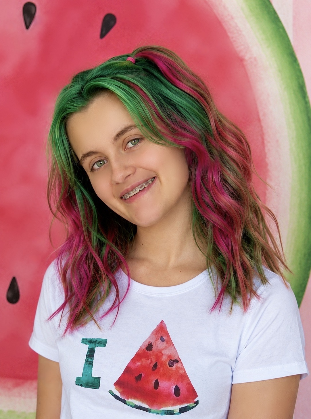 Girl with pink and green watermelon-inspired hair wearing a watermelon T-shirt at a kids watermelon jewelry party.